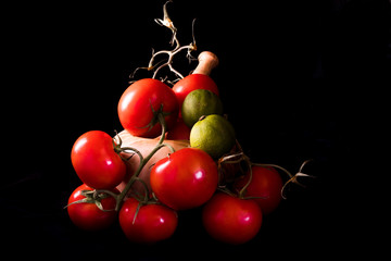 large red and ripe tomatoes with a mortar and pestle in olive wood on black background