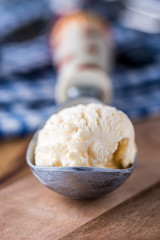 A single scoop of vanilla ice cream on a wooden board