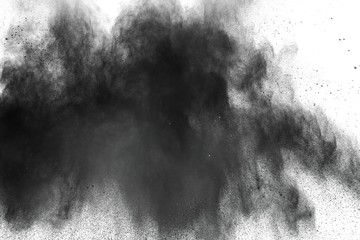 Black powder explosion against white background.Closeup of black dust particles explode isolated on white background.