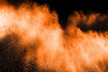 abstract explosion of orange dust. abstract orange  powder splatter on black  background. Freeze...