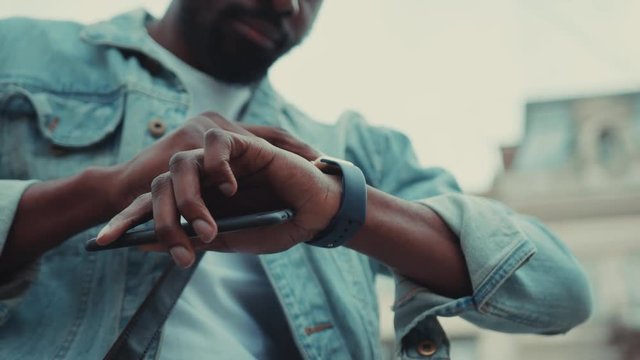 hands young African American man use smartwatch at the street business hold phone shopping internet face technology call texting mobile smart attractive cell communication slow motion close up