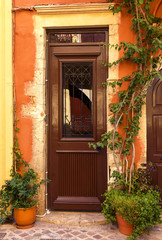 The old arch wooden door in the yellow stone house on the small pedestrianized paved street on the sunny day