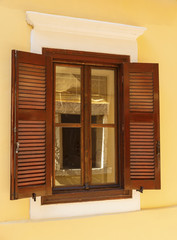 Wooden window with shutters with reflection of another window in glass in a Greek town Chania, Crete