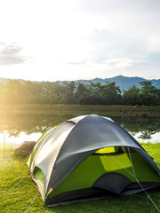 Green camping tent near lagoon in the morning light