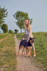 H&uuml;bsche junge Frau steht mit ihren Hunden auf einem Feldweg