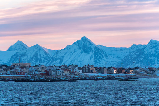 Andenes view from the nordic sea at sunset with a grey pink sky and blue mountain on the back