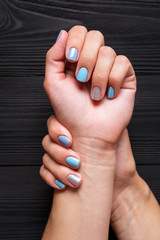 the manicure, blue with silver color, isolated on a black wooden background