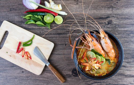 Close up Asian Spicy soup with shrimp in bowl , famous Thai food cuisineม Tom Yum Goong Spicy Sour Soup on wooden table top view