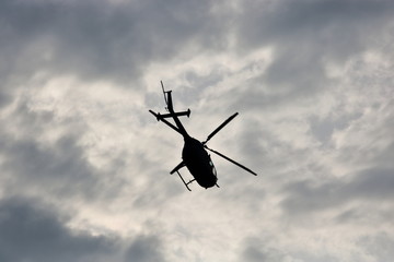 Helikopter na tle zachmurzonego, posępnego nieba, widziany od dołu, leci