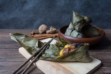 Fototapeta na wymiar Zongzi or Traditional Chinese Sticky Rice Dumplings made of glutinous rice stuffed with different fillings and wrapped in bamboo reed (or other large flat leaves) on wood table.