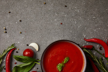 top view of delicious tomato soup and vegetables on grey table