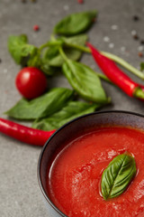 cooked tomato soup, chili peppers, basil and tomato on tabletop