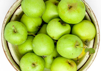 bowl with small green wild not grafted crab apples on white