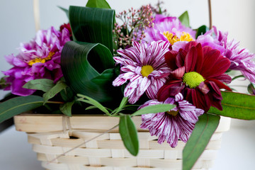 Bouquet of flowers in violet shades in a wattled basket.