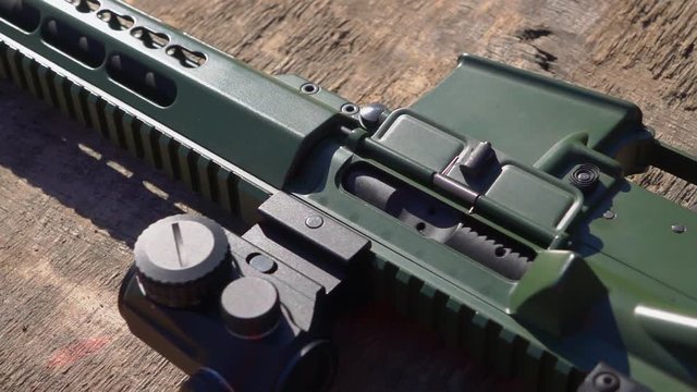 The carbine with a collimator sight rests on the table. Close-up. Dolly shot.