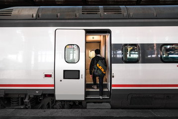 Fototapeta premium Turysta na pokładzie pociągu na stacji kolejowej