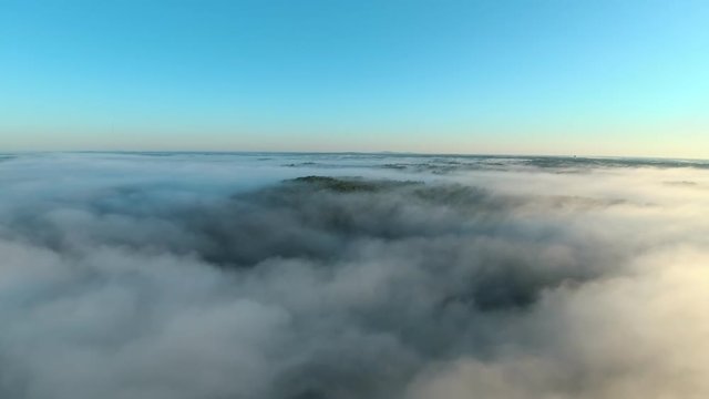 Flying Over Clouds and Fog Away From A Mountain
