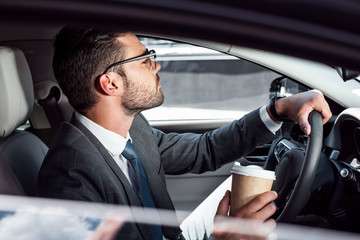 side view of businessman with coffee to go driving car