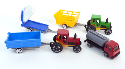 Model toy farm transportation machinery: tractors, trailers and fuel truck. White background.