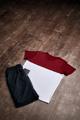 Red and white shirt with black shorts on wooden floor