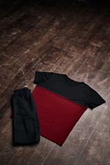 Black and red shirt with black shorts on wooden floor