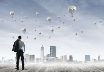 Motivation and inspiration concept with modern cityscape and businessman observing it