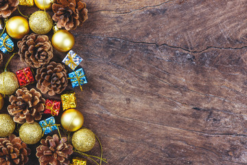 Christmas or New Year background with pine cones,gift box on red ribbon,golden ball of Xmas decorations and fir branches, flat lay, blank space for a greeting text on wooden