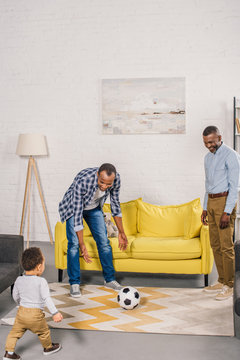 Happy Father, Grandfather And Little Son Playing With Soccer Ball At Home