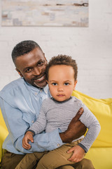 happy african american grandfather and adorable little grandson looking at camera