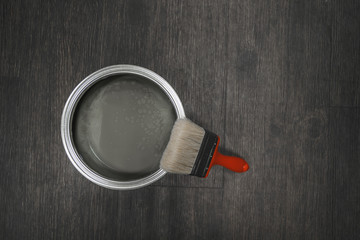 red paint brush with bucket of paint on a black wooden background