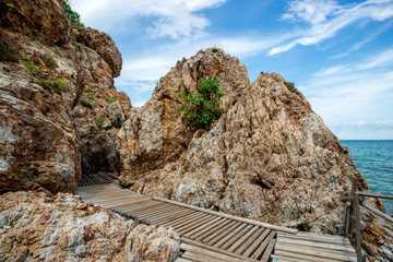 The wooden walkway  beside rock leading to the beach in Thailand