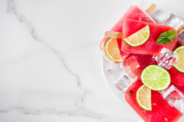 Sweet summer watermelon and lime popsicles with sliced watermelon and mint, on white marble background copy space