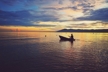 Sunset silhouette with a fisherman at the background at Kande Beach, Nkhata Bay, Lake Malawi 