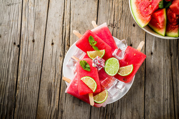 Sweet summer watermelon and lime popsicles with sliced watermelon and mint, on white marble background copy space