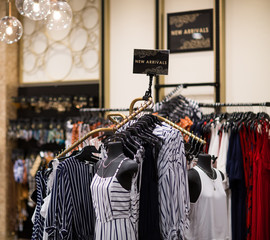 New collection clothes hanging on the rack in the shop- Shopping, fashion, style and people concept