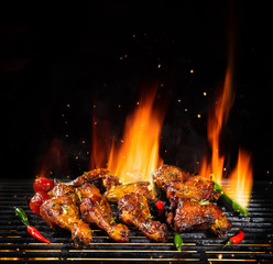 Various chicken meat being grilled, isolated on black