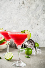 Watermelon margarita cocktail with lime and sliced watermelon, light concrete background copy space