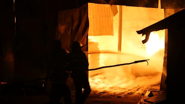 Firefighters In Front Of A Burning Warehouse