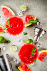 Watermelon margarita cocktail with lime and sliced watermelon, light concrete background copy space