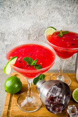 Watermelon margarita cocktail with lime and sliced watermelon, light concrete background copy space