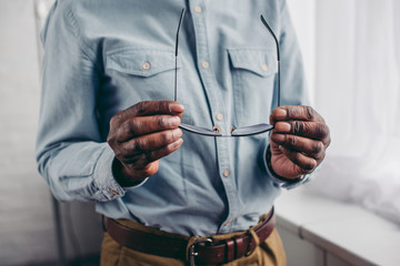cropped shot of senior african american man holding eyeglasses - Powered by Adobe