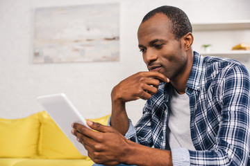 thoughtful african american man using digital tablet at home