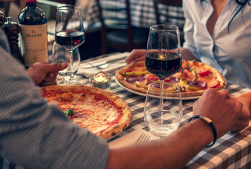 Verliebtes Paar stoßen auf Ihre Lieben an, halten Hand in einem Restaurant und essen Pizza und...