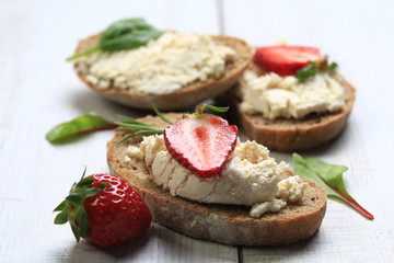 Slices of bread with white cheese and strawberries on top