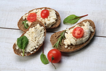 Slices of bread with white cheese next to tomatoes