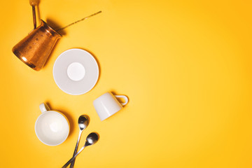 Turkish cezve, espresso cups and plate concept of coffee making and drinking. Yellow background, flatlay, copyspace