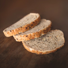 Slices of wholegrain bread on dark ructic wooden  background closeup.