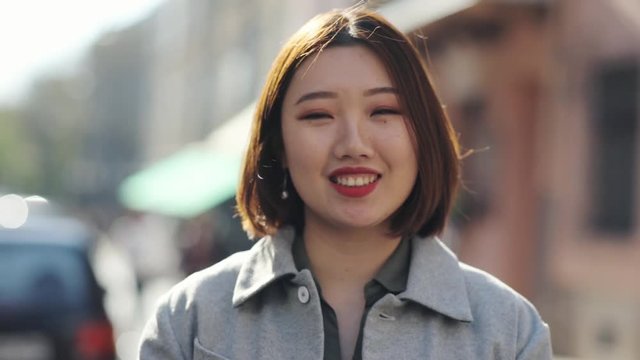 Close up face Asian woman look at camera smile outdoor girl eye happy asian beautiful beauty chinese expression fashion japanese portrait young attractive cute gorgeous hair slow motion