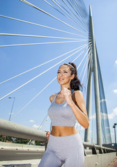 Young fit beautiful girl running outdoor on bridge