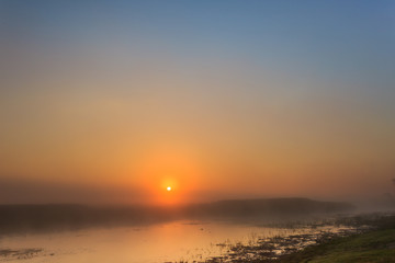 Foggy landscape with sunrise over the river